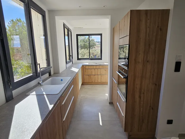 Cuisine en bois avec plan de travail gris et vue sur le jardin